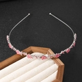 Zilveren dunne hoofdband met roze strass bloemen op een houten sieradendisplay - Pruimenbloesem Rozerood