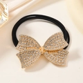 Detailed macro view of a gold rhinestone bow hair tie with elastic black bands - Gold