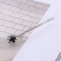 Dettaglio di un fermaglio argentato con strass lucidi e pietra preziosa nera tonda - Nero