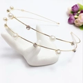 Detailed view of elegant double-layered gold headband with pearls and rhinestones on display - Gold