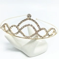 Sparkling gold tiara headband with white rhinestones on a ceramic display hand - Gold