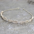 Elegante cerchietto dorato con strass e design a incrocio su una superficie di legno - Oro con Strass