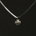 Macro-opname van een kruishanger van titaniumstaal met donkere schelp op zwarte stof - Staal Kleur Schelp Kruis Ketting (B3015)
