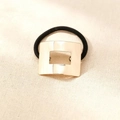 Close-up of golden square metal ornament on high-elasticity black hair tie - Gold