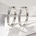 Funkelnde Creolen in Silber mit herzförmigen Diamanten auf minimalistischem Steinhintergrund - Silber