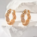Luxurious gold twisted hoop earrings with micro-paved zircons on a white stone background - Gold White Zirconia (E1203)