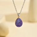 Macro d'un pendentif goutte d'eau en résine pailletée violette avec lunette dorée et chaîne - Argent Violet Brillant