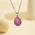 Macro d'un pendentif goutte en druzy fuchsia avec bordure dorée sur chaîne argentée - Argent Rose Vif