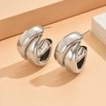 Dettagli macro di orecchini a cerchio a C multistrato intrecciati in stile minimalista - Orecchini a Bottone d'Argento