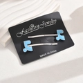 Detail of light blue musical note hair clips on a card with elegant long shadows - Blue