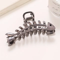 Detalle de una pinza para el cabello con forma de espina de pescado en metal oscuro y cristal - Color gunmetal