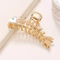 Detalle de la pinza para el cabello dorada con forma de espina y un diamante azulado - Dorado