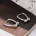Minimalist silver U-shaped hoop earrings with metal beads on a lace and magazine background - Silver (E1204)