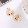 Primer plano de pendientes de aro dorados con forma de corazón sobre fondo blanco - Dorado