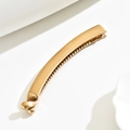 Macro view of matte golden alloy banana hair clip with non-slip teeth and round ball buckle - Gold
