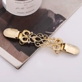 Vintage golden hollow flower cloak clip with white rhinestones on a fashion magazine - Gold
