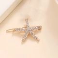 Dettaglio del fermaglio a stella marina dorata con strass bianchi brillanti su metallo - Oro