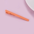 Detail view of a matte orange bobby pin with a serrated grip on a soft purple backdrop - Orange