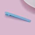 Detail view of sky blue matte alligator hair clip on a pink background for styling - Blue
