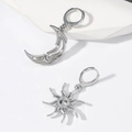 Detalle macro de pendientes asimétricos de sol y luna con diseño hueco y circonita - Plateado