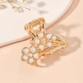 Elegant gold flower hair claw clip with white pearls and leaves in a scenic setup - Gold Flower