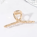 Detalle macro de la pinza de pelo de metal dorado grande con diseño hueco retorcido - Dorado