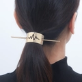 Detail showing a minimalist gold-finished lightning pulse hair slide on tied hair - Short Gold
