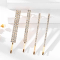 Lot de quatre barrettes dorées élégantes avec strass blancs brillants de largeurs variées - Ensemble Or