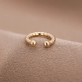 Minimalistischer goldener Ear Cuff mit Spiralstruktur und Metallkugeln auf Strickhintergrund - Gold (A8101)