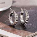 Elegantes pendientes de aro geométricos plateados con circonitas sobre fondo de revista chic - Plateado