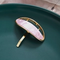 Detailed macro view of an oval pink marble resin hair hook with a gold alloy frame - Purple