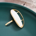 Detail of a geometric acetate ponytail hook featuring a golden oval frame and shell texture - Beige