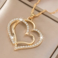 Gros plan du collier pendentif double cœur doré avec strass sur un coffret cadeau - Collier Or