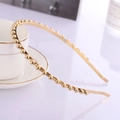 Elegante cerchietto in metallo dorato con micro perline, esposto accanto a una tazza di ceramica - Oro