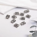 Vintage hollow silver dreadlock beads with ornate floral engraving on white background - Antique Silver