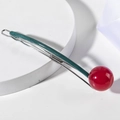 Detalle de una pinza geométrica para el pelo con bola de resina roja sobre seda - Verde y Rojo