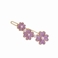 Eleganter goldener Haarclip mit drei lila Blumen und weißen Perlen auf weißem Hintergrund - Blumenstil