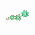 Detalle de la pinza dorada con motivos de trébol verde y elegantes perlas blancas - Flor Verde