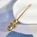 Détail macro d'une barrette dorée ornée de strass étincelants en forme de goutte champagne - Champagne (E4305)