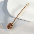 Macro detail of elegant golden hair clip with amber crystal and sparkling rhinestones - Champagne