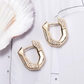 Minimalistische geometrische Goldohrringe mit Zirkon-Pavé auf weißem Muschelhintergrund - Gold
