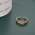 Anillo geométrico dorado con circonitas sobre fondo verde oscuro de estilo moderno - Estilo Dorado (D7119) / Dorado