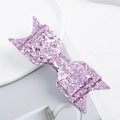 Detailed macro view of a pink glitter bow accessory on a clean minimalist white plate - Bow / Pink
