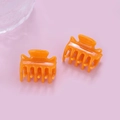 Makroaufnahme von zwei glänzenden orangefarbenen Mini-Haarklammern auf Rosa mit Eisdeko - Hellorange