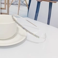 Vue détaillée d'un serre-tête en strass argentés posé sur une tasse en céramique - Argent Strass AB