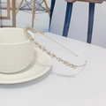 Cerchietto dorato con perline e strass appoggiato su una tazza di ceramica bianca - Stile Perla Dorato (I9206)