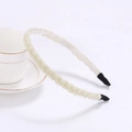 Close-up of cream beaded braided headband resting on a white coffee cup edge - Ivory