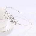 Detailansicht eines silbernen Haarreifs mit Kristallen auf einer weißen Tasse - Blattzweig-Stil / Silber