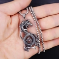 Hand die vintage roestvrijstalen draakhanger vasthoudt met Keltische knoop en boxketting - Draak met Roestvrijstalen Ketting
