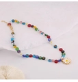 Gros plan d'un collier de perles colorées avec pendentif marguerite sur fond de tissu blanc - Multicolore
